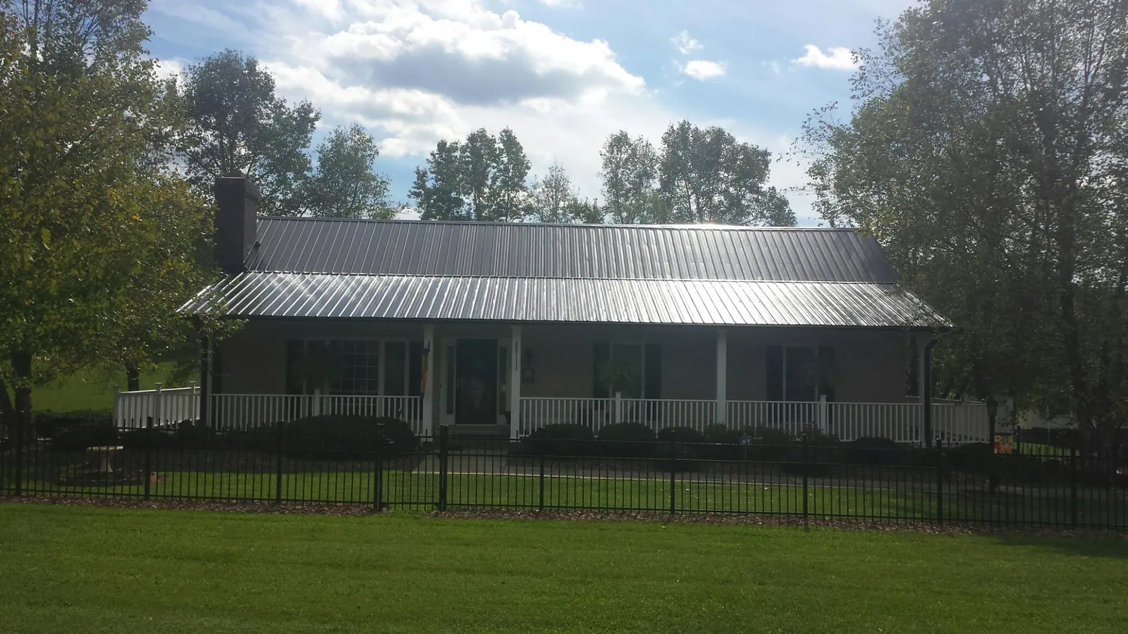 Gray metal roof on a brick ranch with a full width front porch — Gutter Guard Installation work by our crew in Waupun