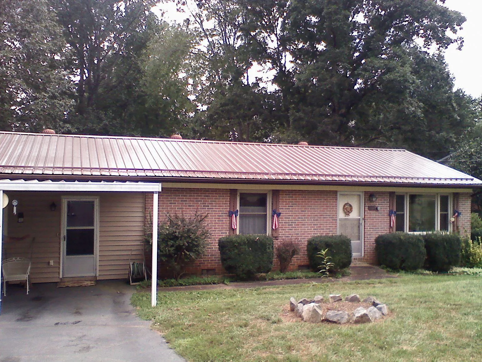 Bronze metal roof and carport on a brick ranch home — Roof Repair work by our crew in Waupun