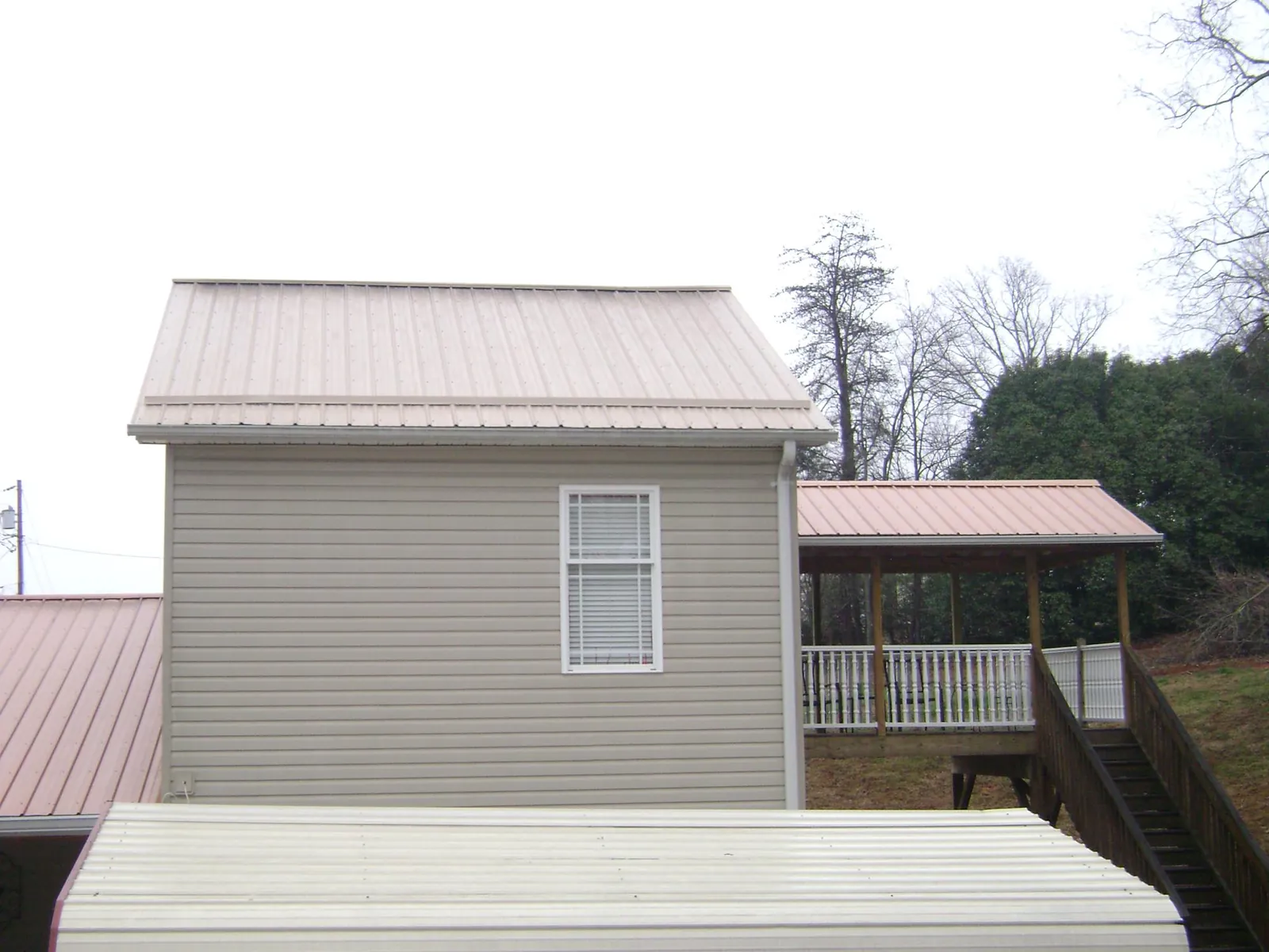 Tan metal roofs on a two story addition and attached porch, from a Roof Replacement job in Waupun